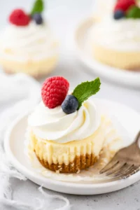 Mini cheesecake on plate with cupcake wrapper peeled from edges