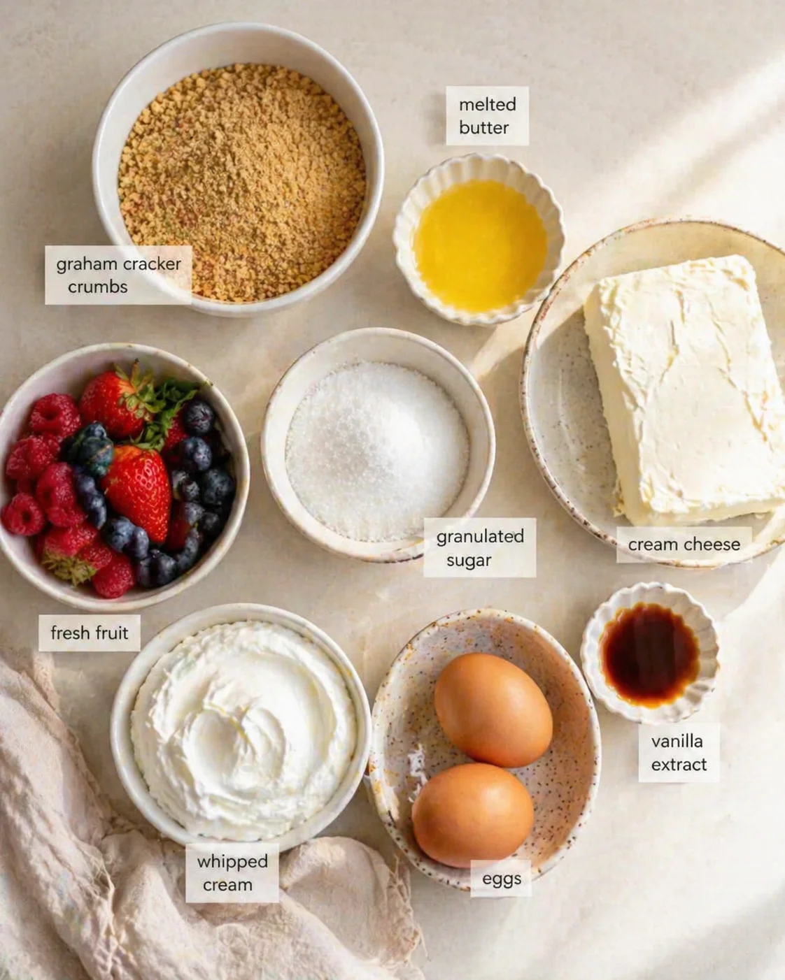 top-down flat lay of cheesecake ingredients with labeled bowls