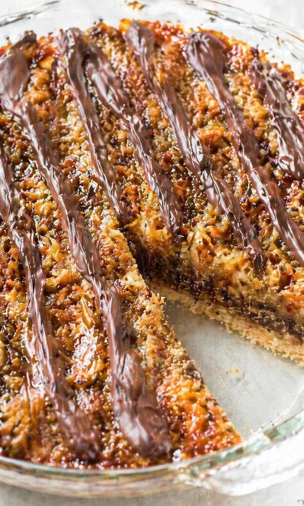 Close-up of a glass pie dish with slices of coffee cake topped with chocolate drizzle.