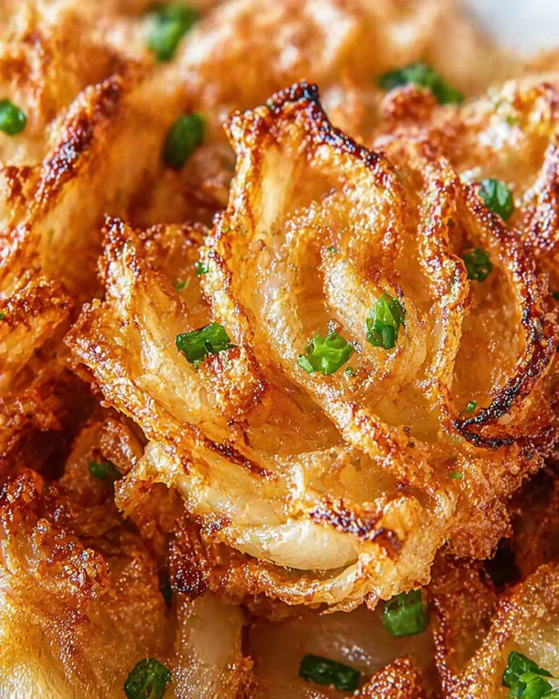 close-up of golden, crispy onion rings garnished with chopped parsley