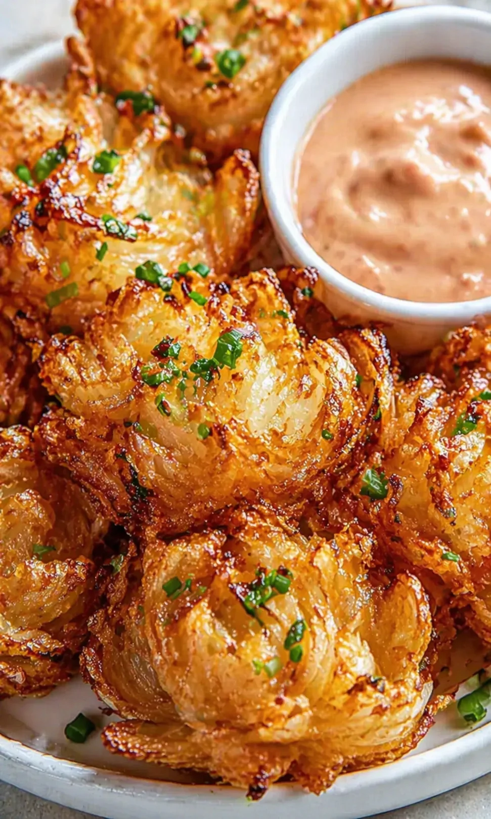 Close up of golden crispy potato bites with a small bowl of creamy dipping sauce