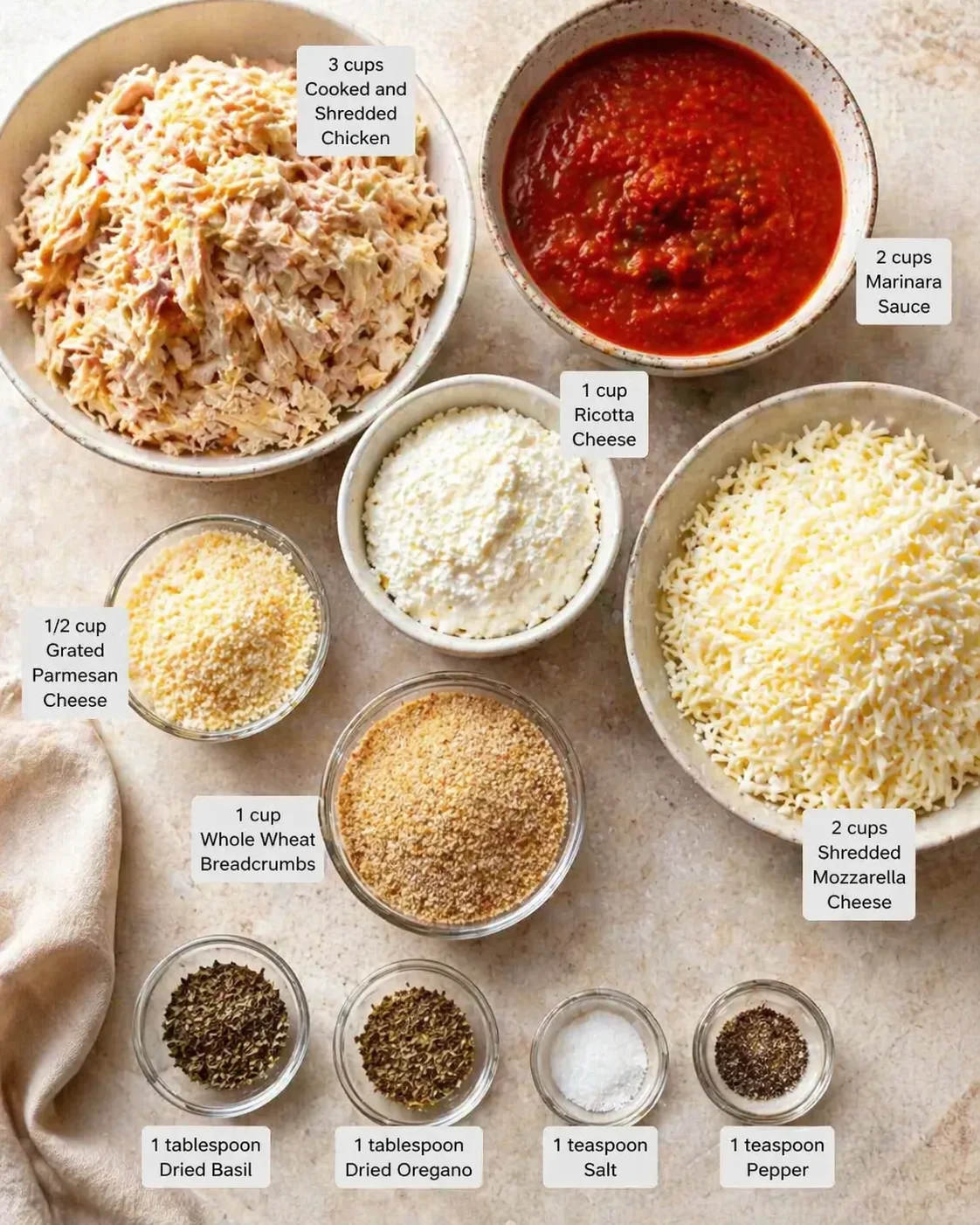 Top-down view showing labeled bowls of chicken, sauces, cheeses, breadcrumbs, and spices for chicken parmesan.
