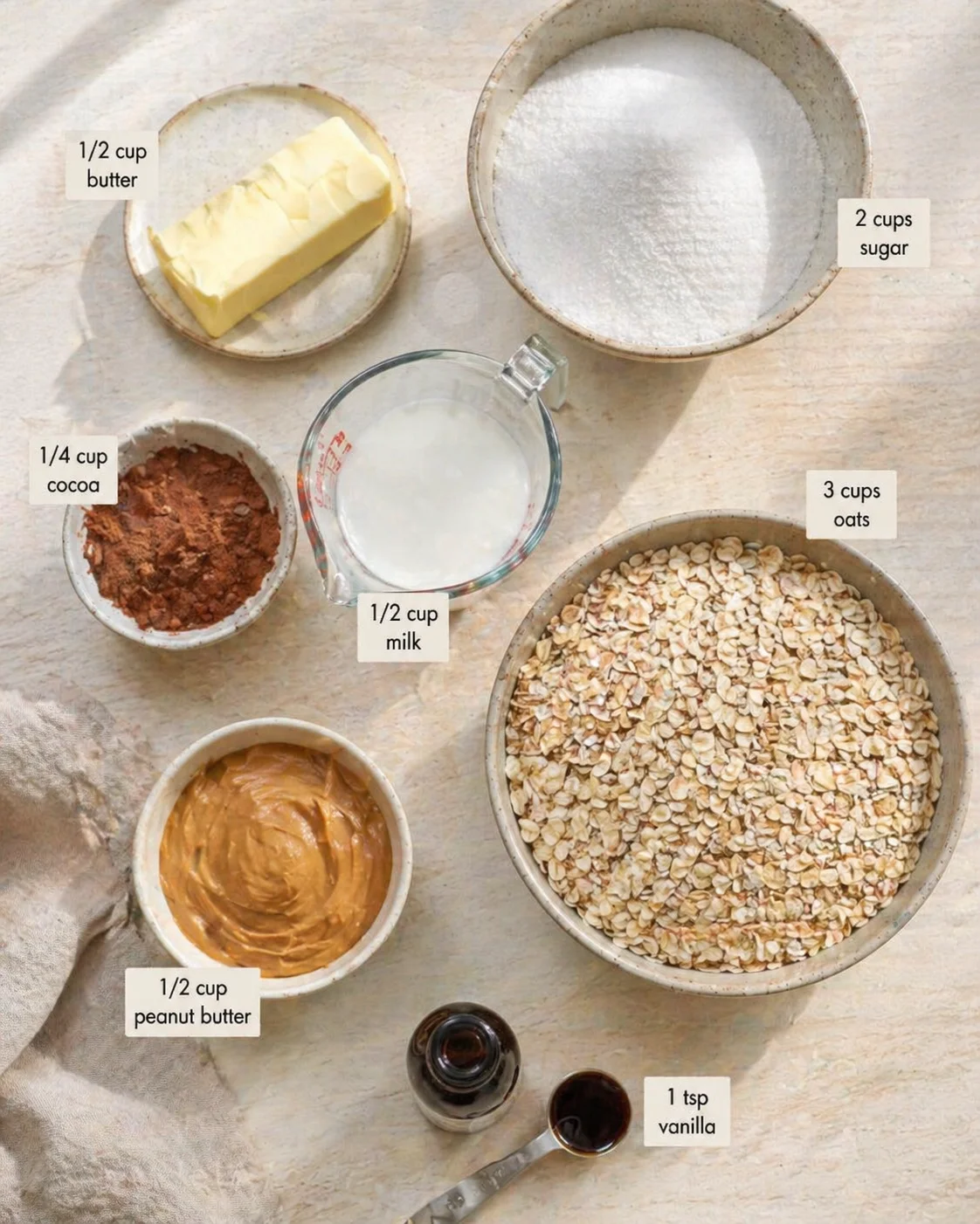 Overhead view of baking ingredients: oats, peanut butter, cocoa, butter, sugar, milk, vanilla.