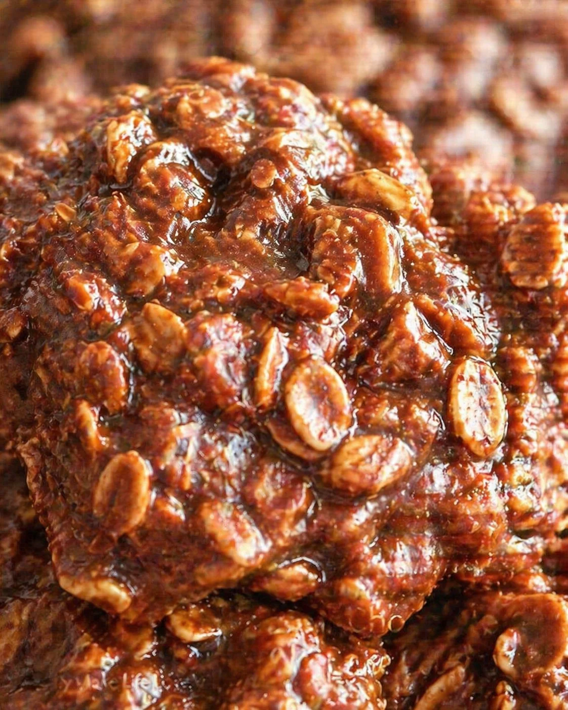 close-up of glossy caramel-coated peanut clusters piled together on a textured surface.