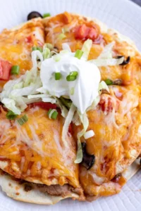 Mexican pizza topped with sour cream serve don white plate