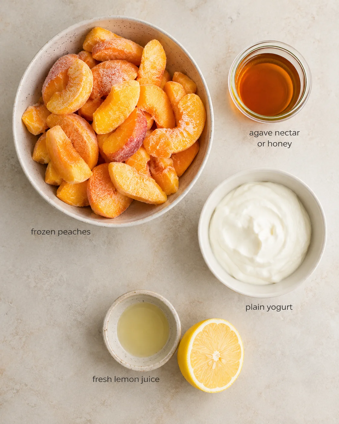 Overhead view of frozen peach slices with honey, yogurt, lemon juice, and a lemon half.