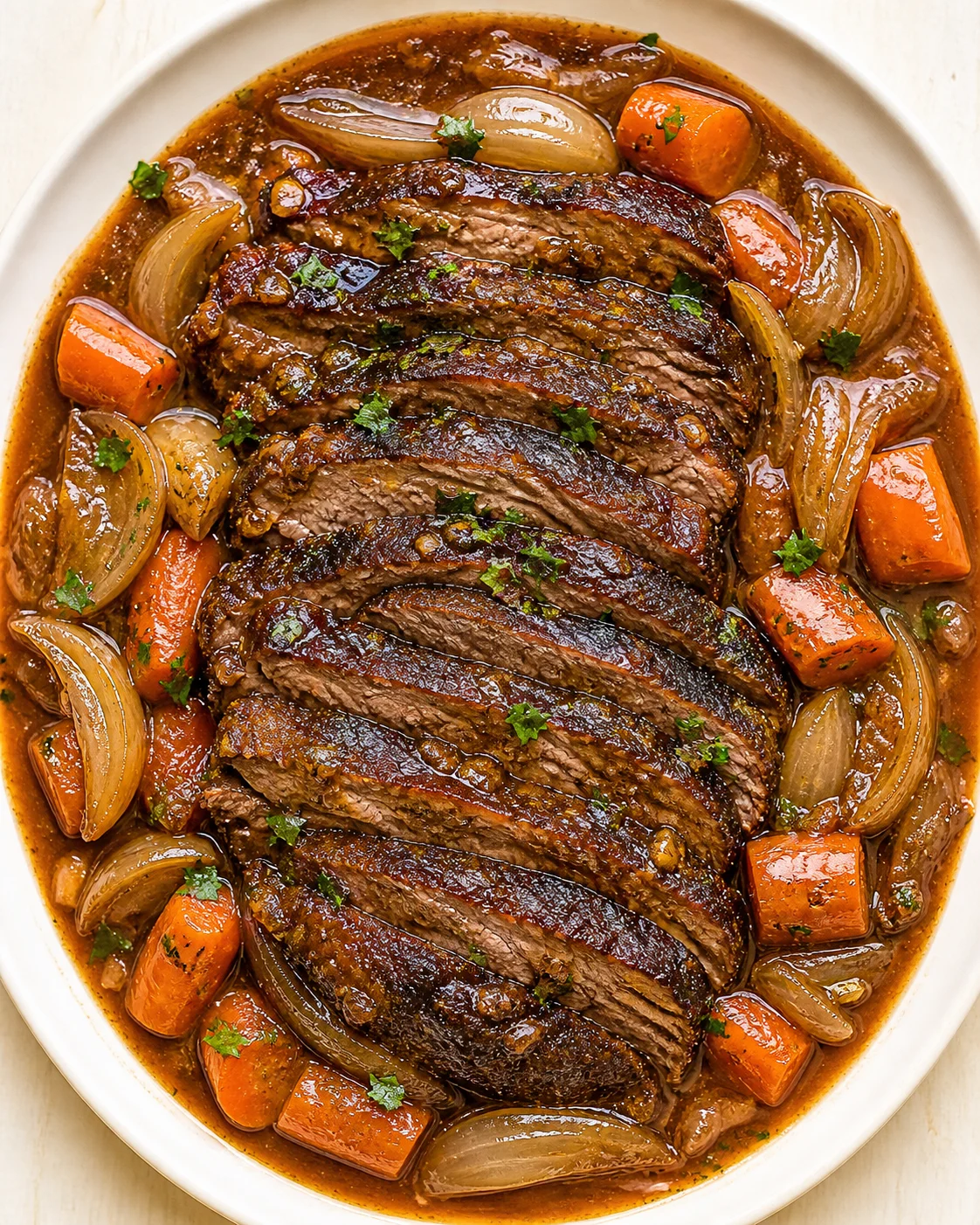 braised-beef-slices-with-veggies sliced beef in glossy brown sauce with onions and carrot chunks on a white plate