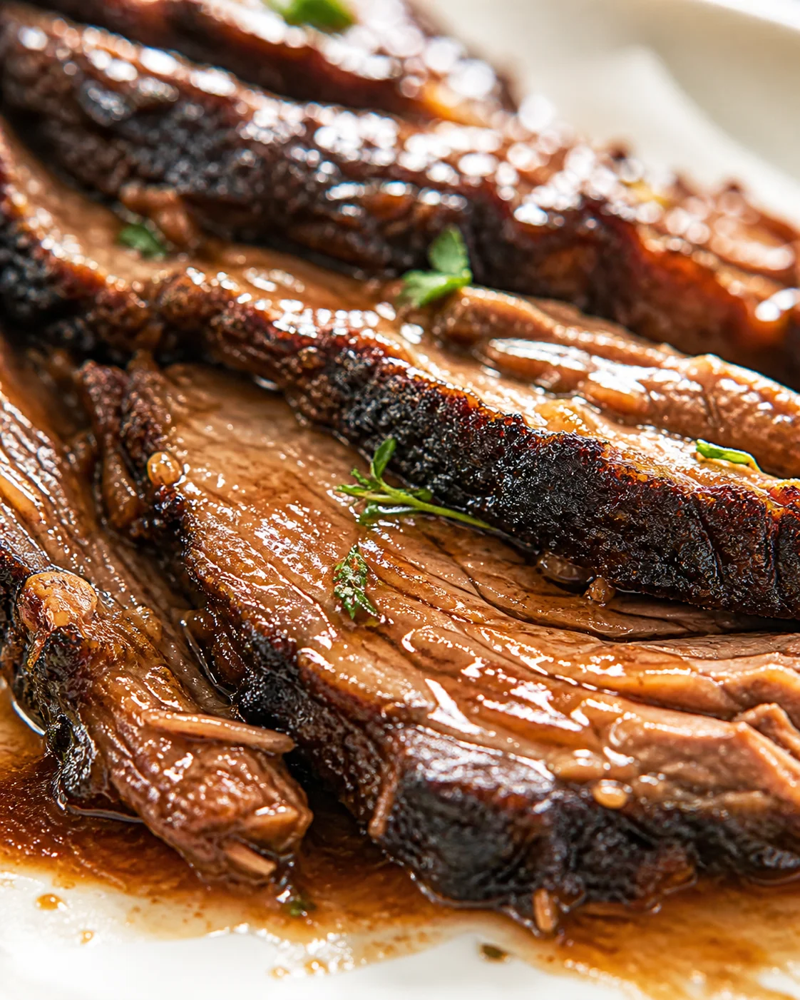smoky-bbq-ribs-closeup Close-up of glossy smoked BBQ ribs with dark crust and juicy meat, garnished with herbs.