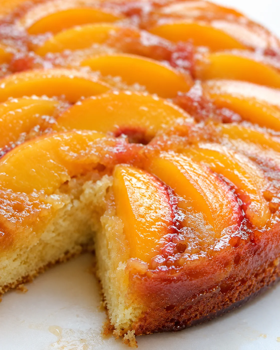 close-up of a peach-topped cake with sliced peaches arranged in a circular pattern and a golden crust