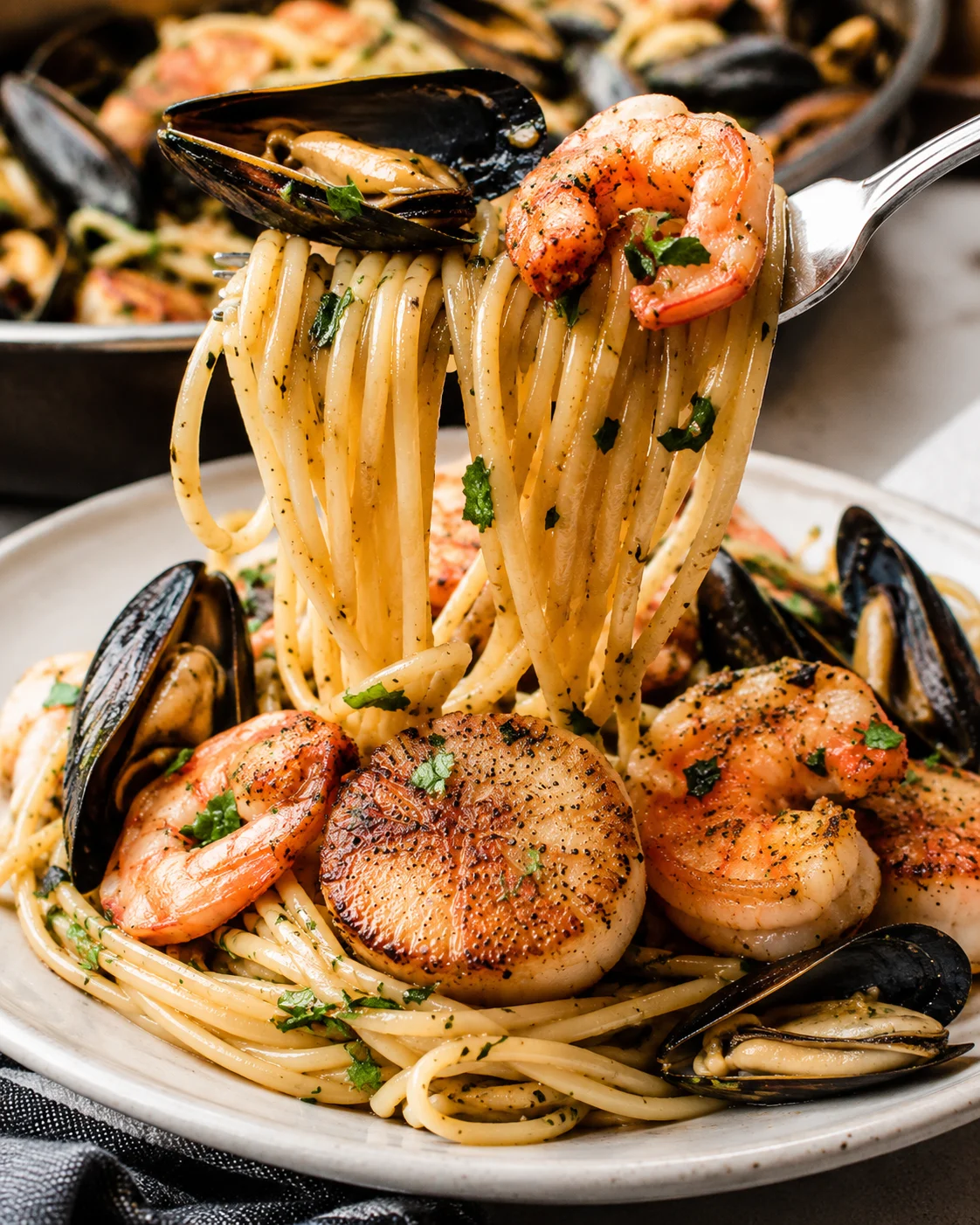Close-up of seafood pasta with shrimp, mussels, and herbs on a plate