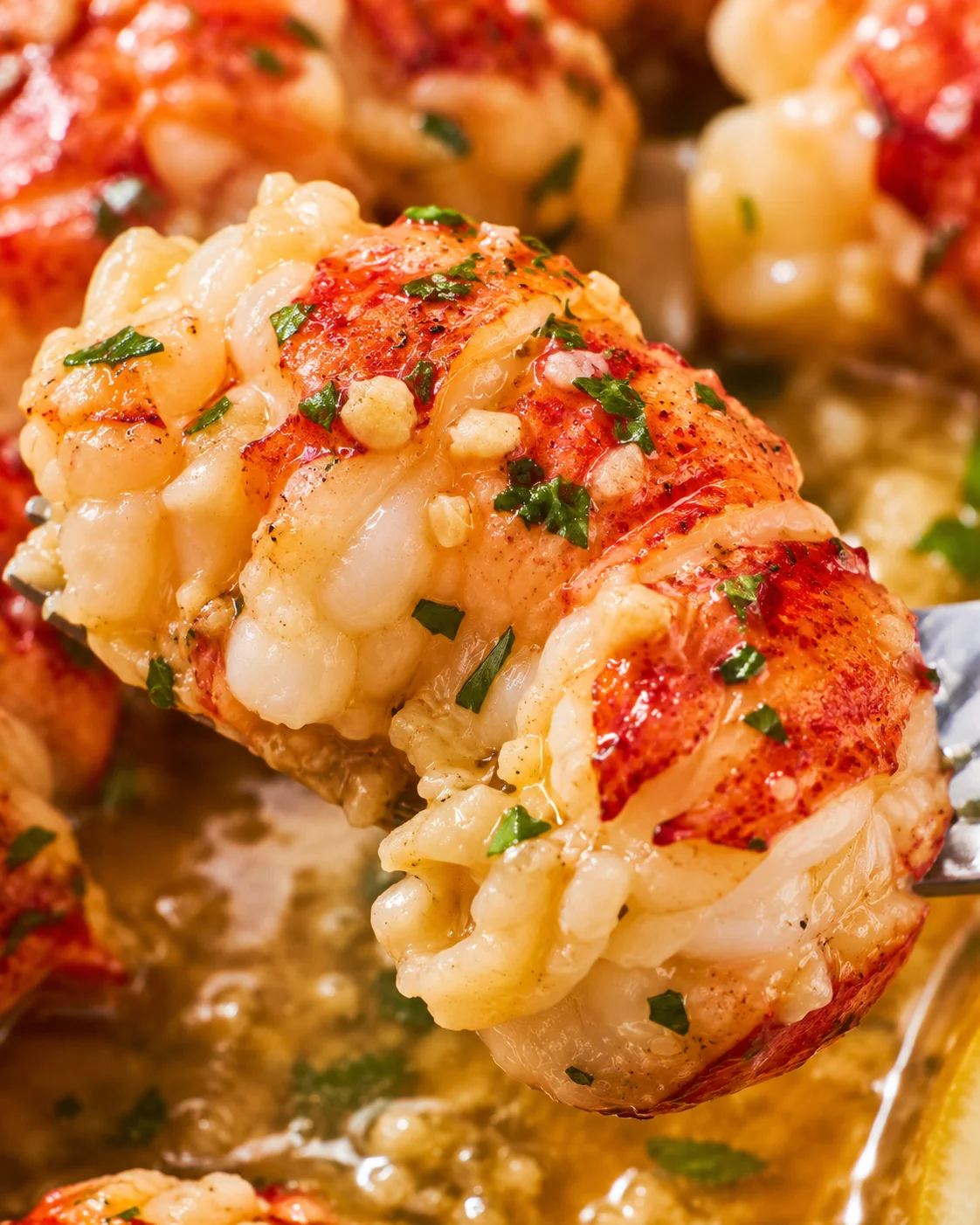 Close-up of perfectly cooked lobster tail drizzled with garlic butter and herbs