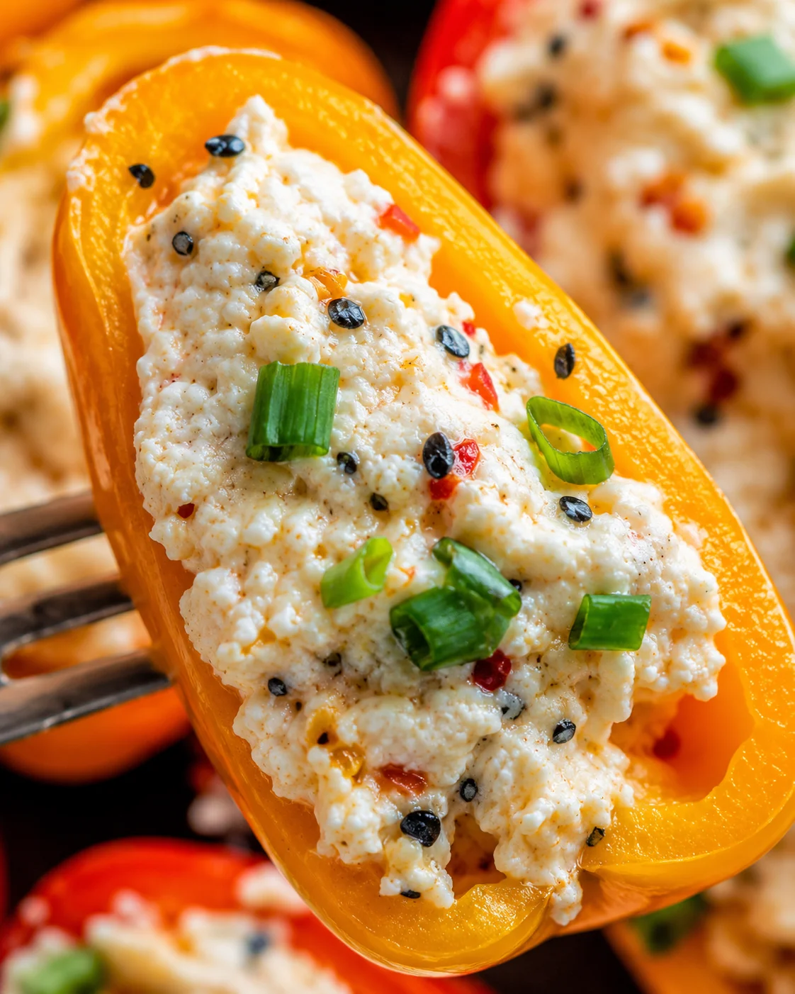 Colorful mini peppers filled with cheese and topped with seasoning and scallions.