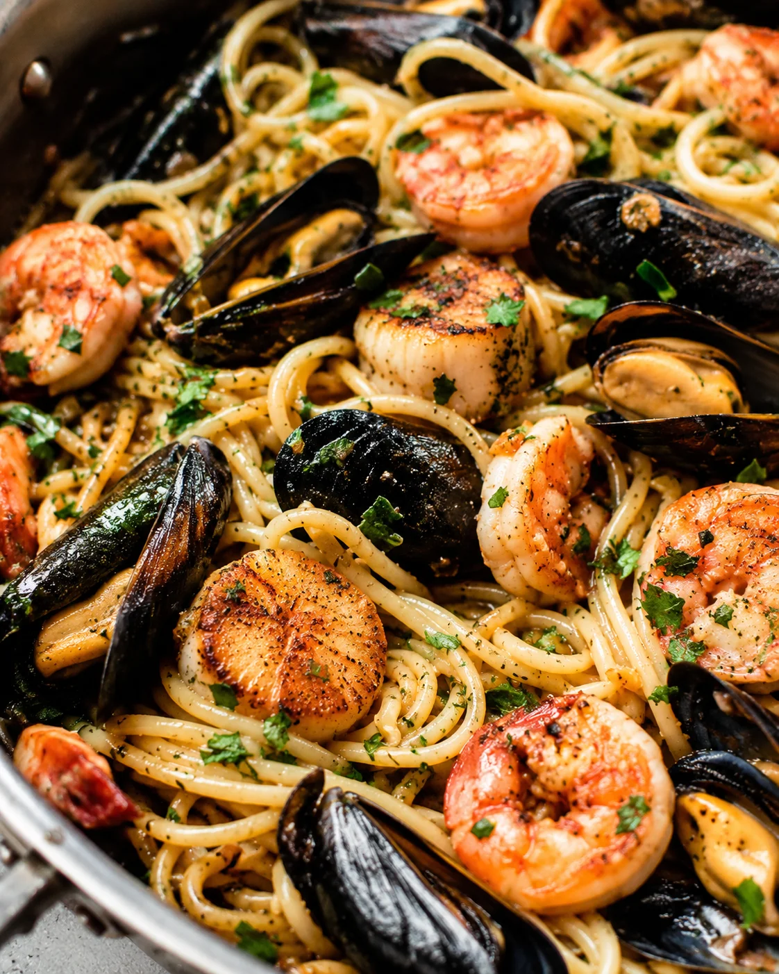 Close-up of cooked seafood pasta with mussels, shrimp, and scallops garnished with herbs