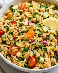 Colorful lemon orzo chickpea salad with fresh vegetables and lemon slices