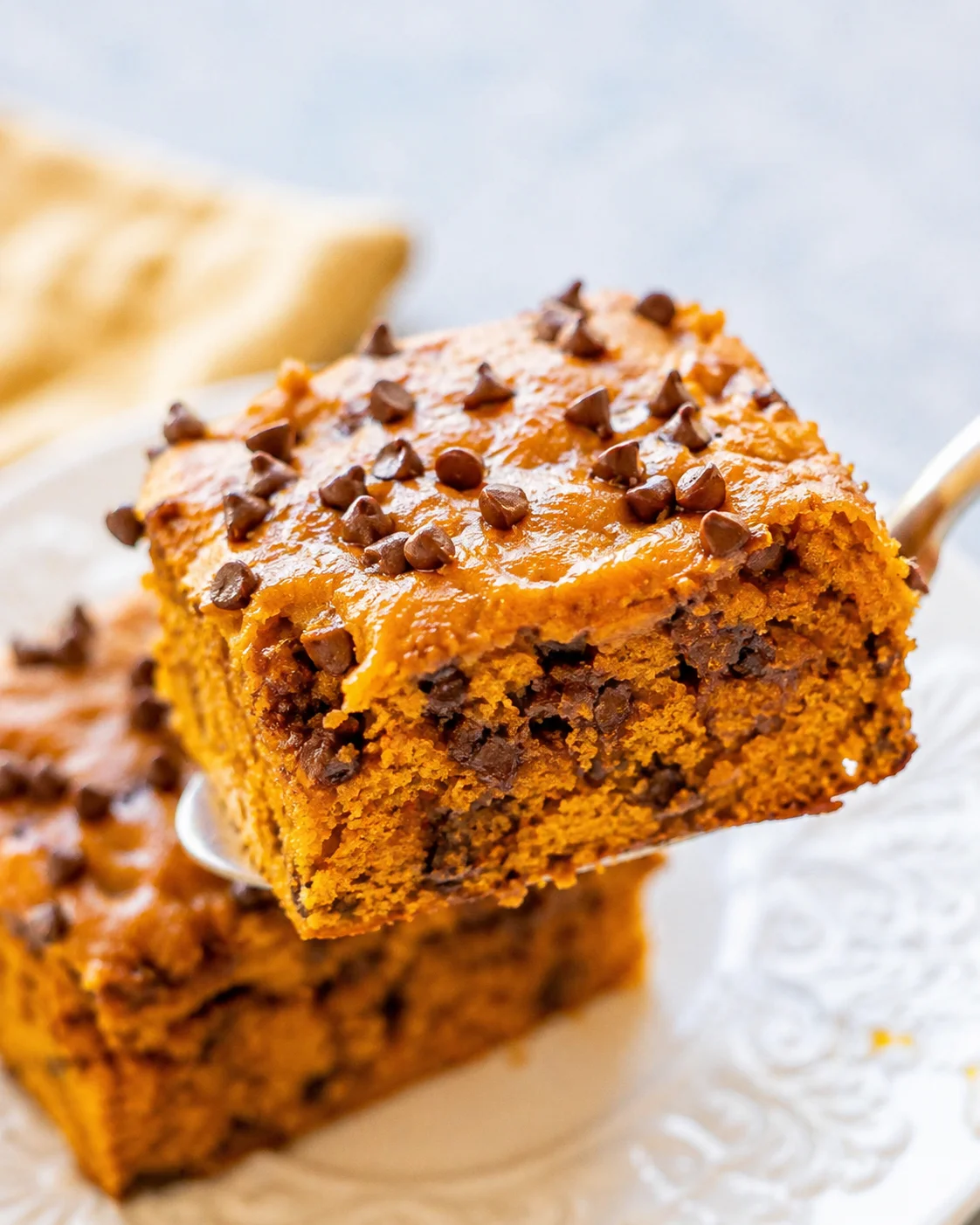 Close-up of moist pumpkin cake with chocolate chips and creamy frosting.
