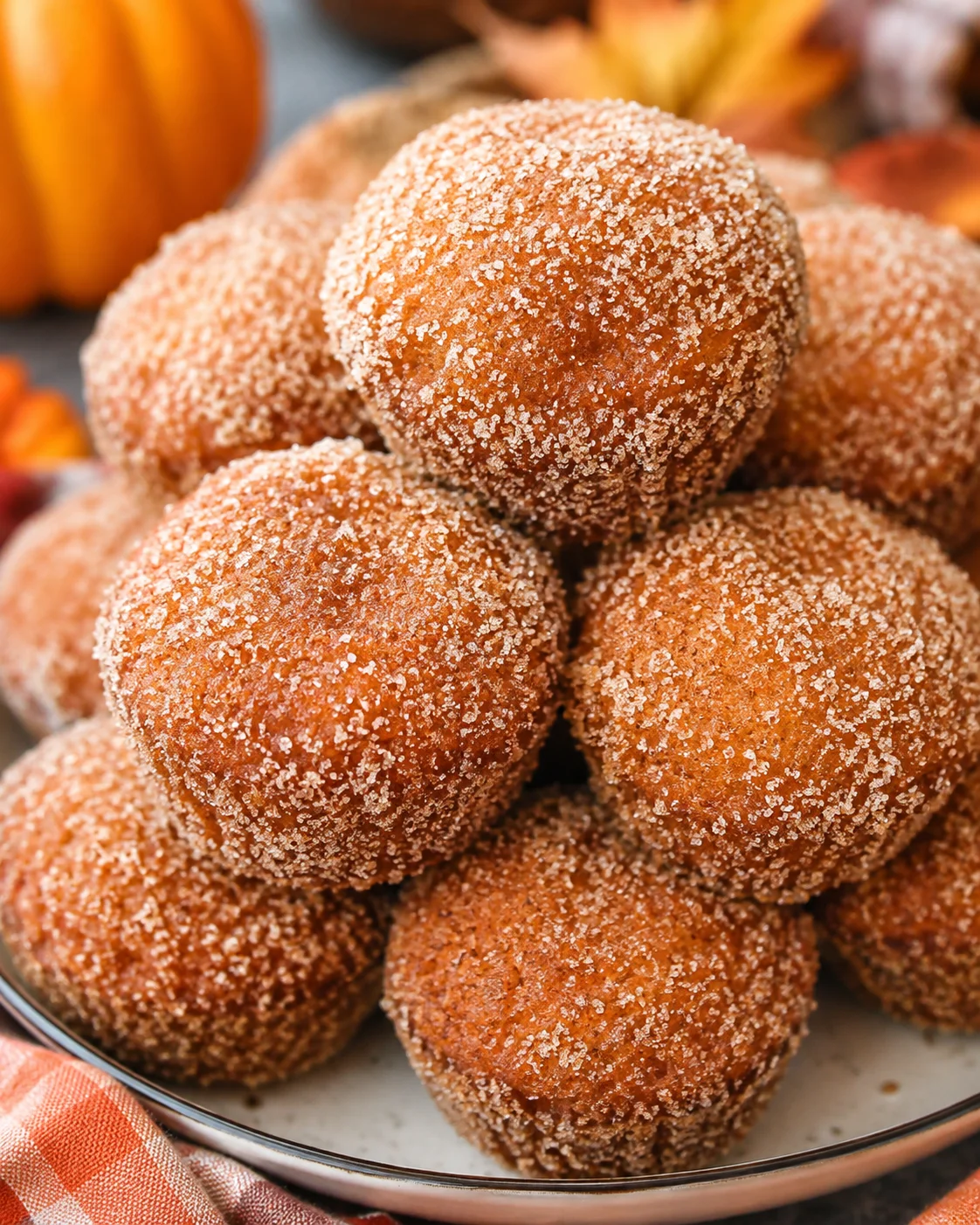 Close-up of cinnamon-sugar coated pumpkin donut muffins on a plate.