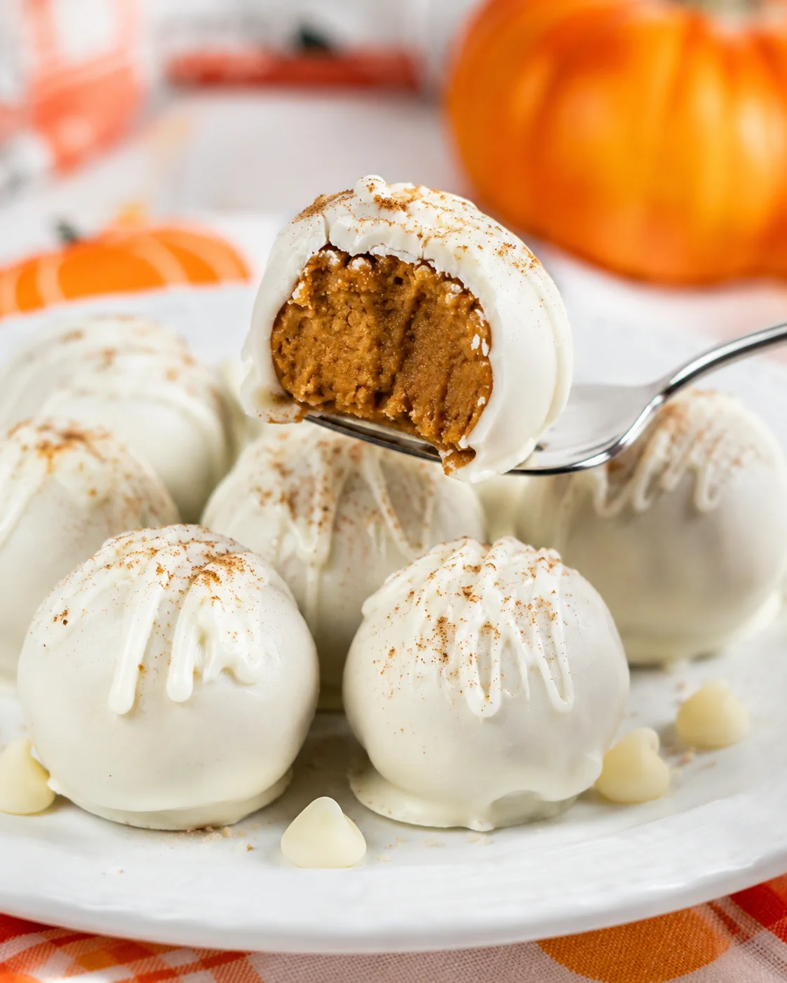 Delicious white chocolate-coated pumpkin cheesecake balls for fall treats.