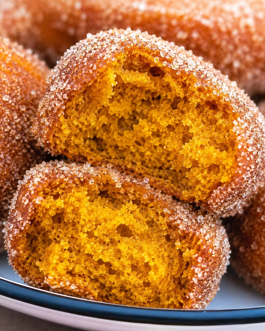 Close-up of fluffy pumpkin muffin with cinnamon sugar coating, sliced open.