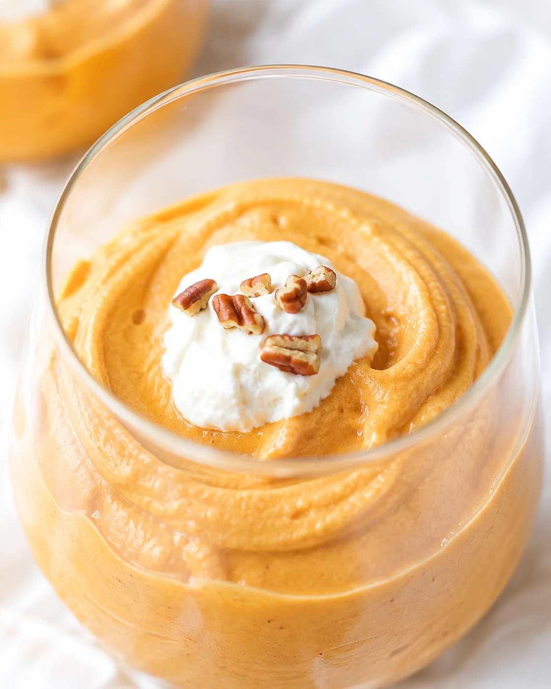 Delicious pumpkin fluff served in a glass with whipped cream and chopped pecans.
