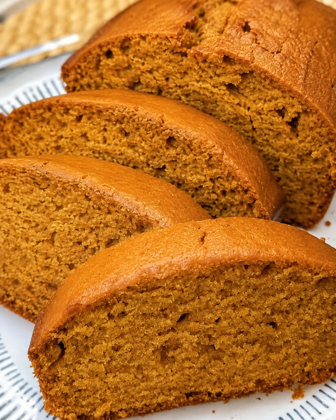 Close-up of moist, golden pumpkin bread slices with a cozy Fall texture.