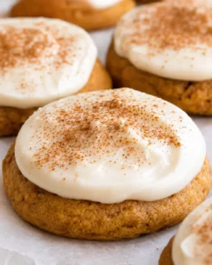 Close-up of soft pumpkin cookies topped with creamy frosting and cinnamon sprinkles