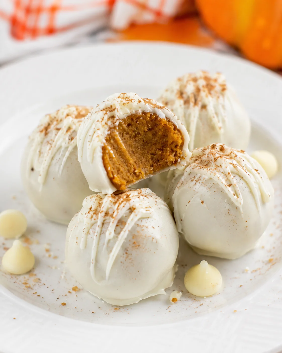 Creamy white chocolate-coated pumpkin balls with pumpkin filling inside, perfect for fall.