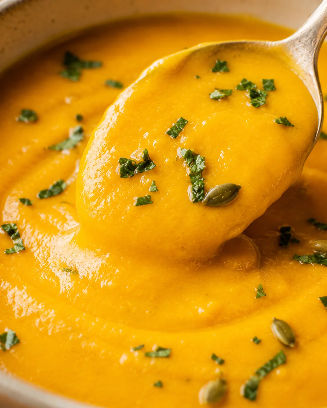 spoonful of butternut squash soup showing creamy texture and parsley