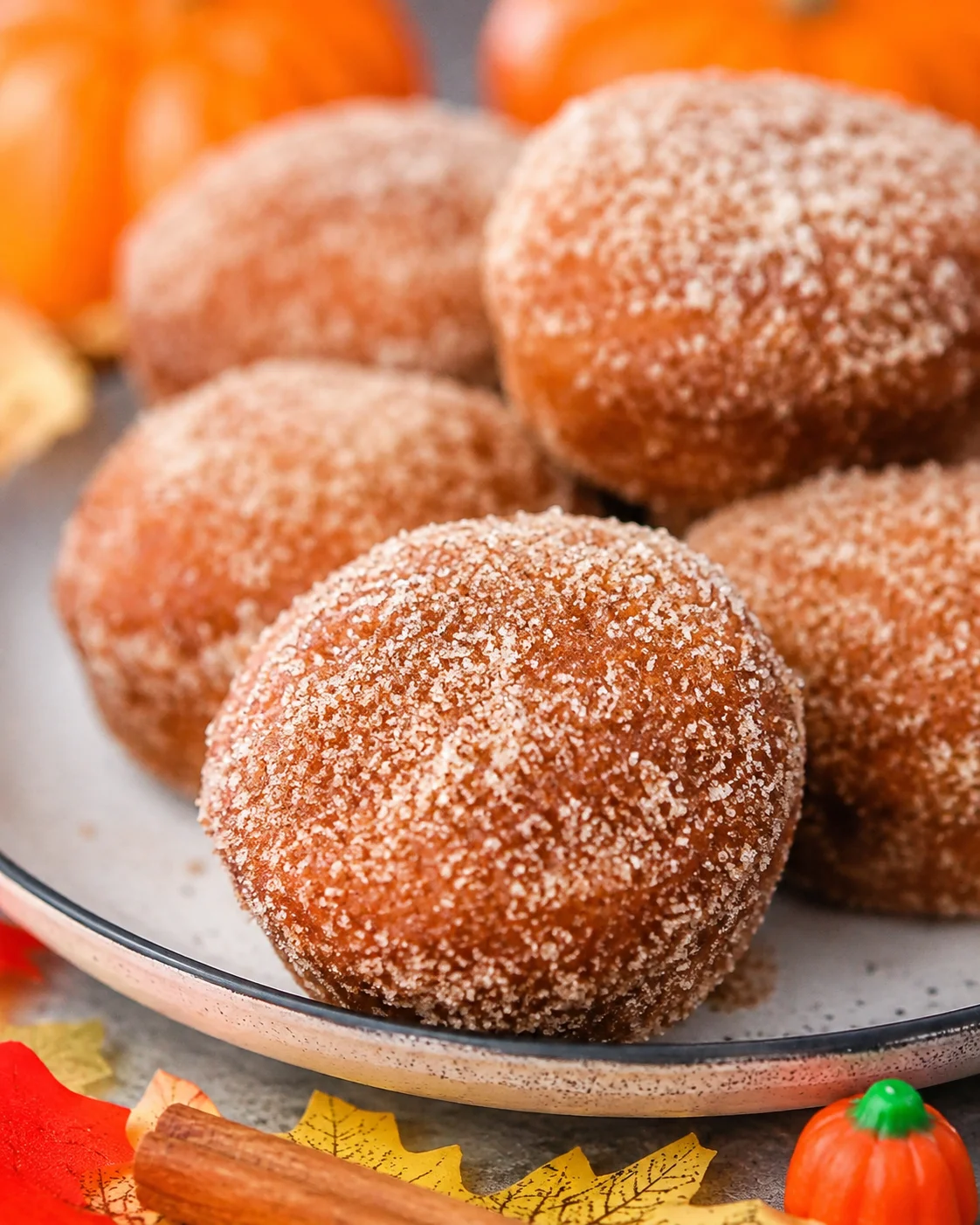 Close-up of cinnamon sugar coated pumpkin donut muffins on a plate.
