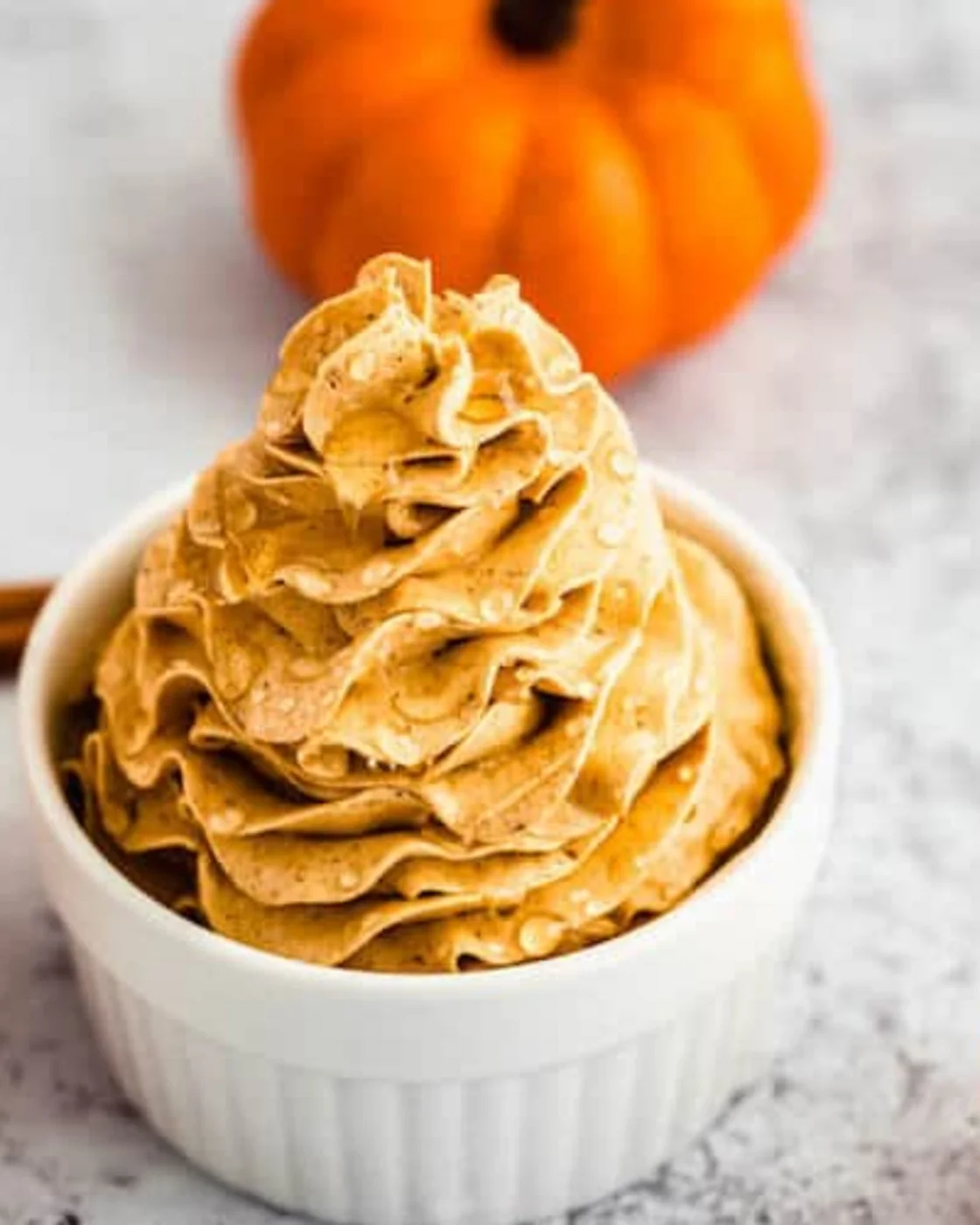Creamy whipped pumpkin spice honey butter with a pumpkin in the background